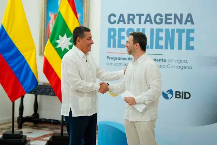 Representantes de la Alcaldía de Cartagena y el BID se saludan frente a un aviso del programa Cartagena Resiliente