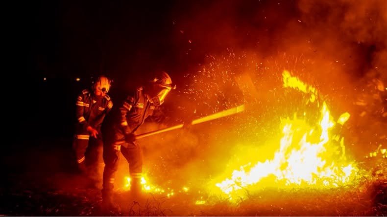 Dos bomberos combaten un incendio forestal durante la noche