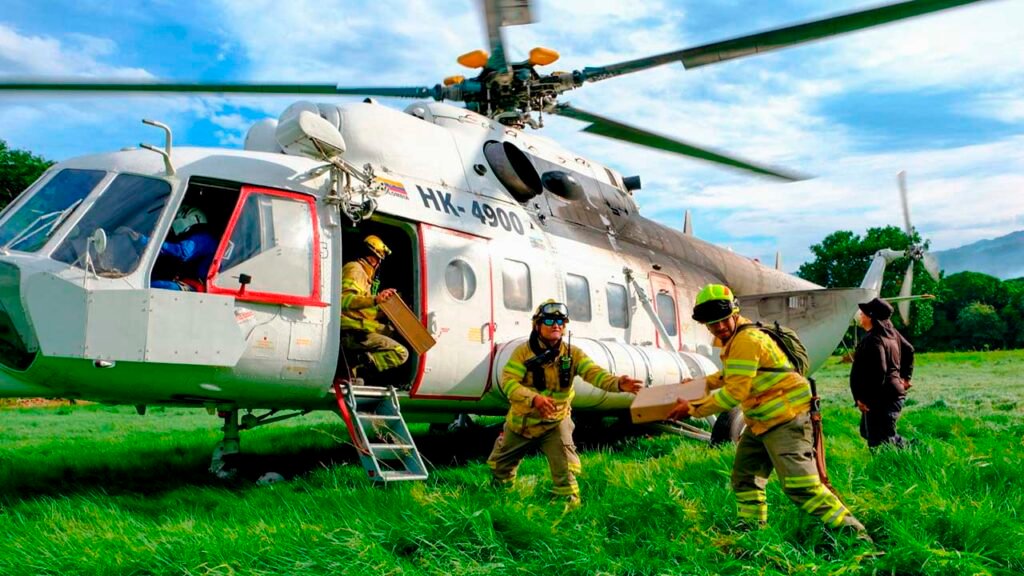 Bomberos cargan suministros en un helicóptero de la UNGRD durante la atención de los incendios en Tolima