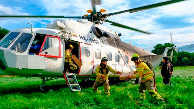 Bomberos cargan suministros en un helicóptero de la UNGRD durante la atención de los incendios en Tolima