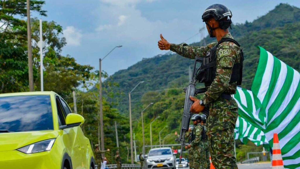 Un soldado armado hace una señal con el pulgar a los conductores en un puesto de control en una carretera de montaña