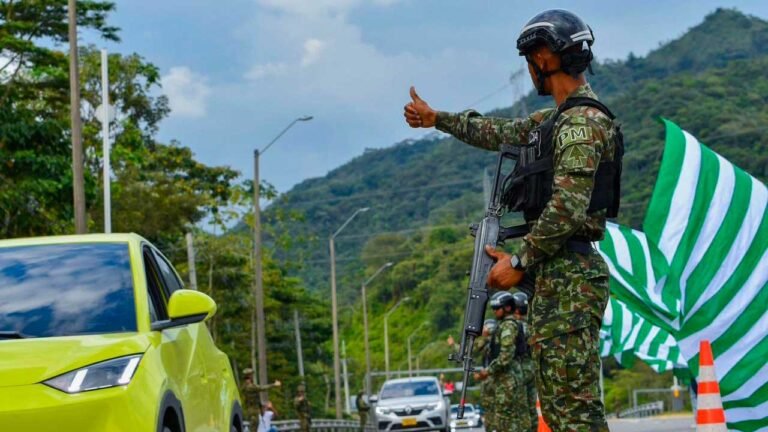 Un soldado armado hace una señal con el pulgar a los conductores en un puesto de control en una carretera de montaña