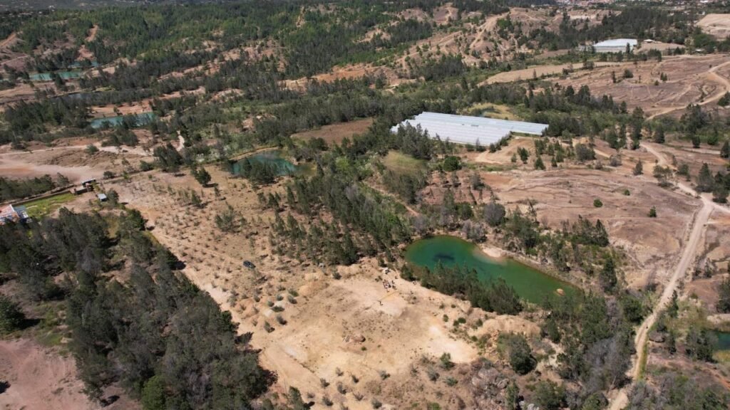 Vista aérea de un terreno seco con poca vegetación y una pequeña laguna, afectado por la sequía