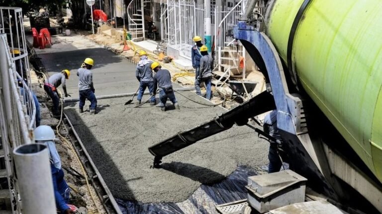Trabajadores funden pavimento rígido con una mezcladora de concreto en la vía alterna de la Carrera 90A, en Villa Estrella