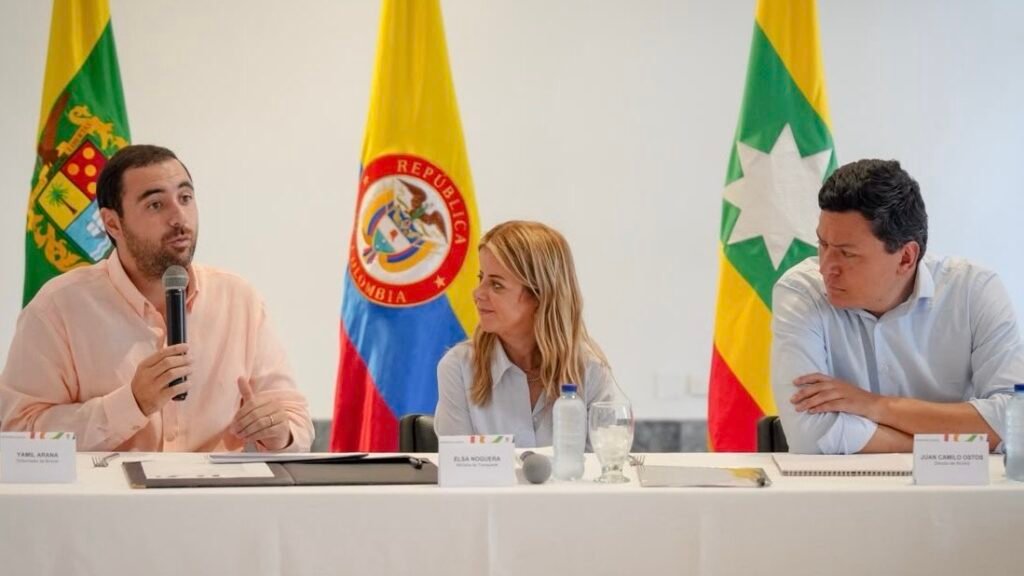 El gobernador Yamil Arana habla con un micrófono junto a la ministra de Transporte, Elsa Noguera, y el director del Invías, Juan Camilo Ostos, en una mesa de trabajo