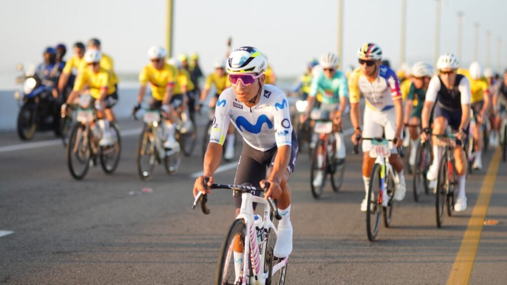 Nairo Quintana, con uniforme blanco y azul, encabeza un grupo de ciclistas sobre un puente de Cartagena al amanecer