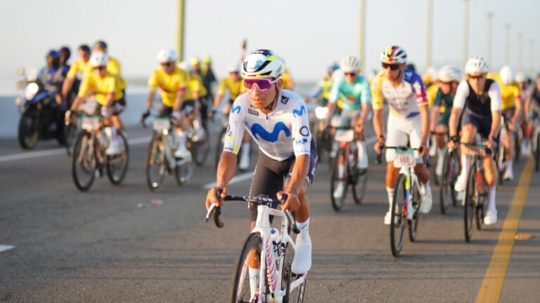 Nairo Quintana, con uniforme blanco y azul, encabeza un grupo de ciclistas sobre un puente de Cartagena al amanecer