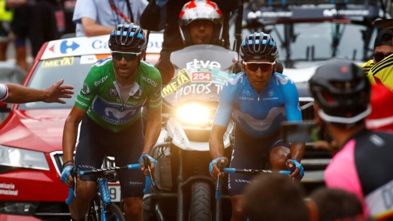 Nairo Quintana, con el uniforme azul del Movistar Team, pedalea junto a un compañero de equipo con maillot verde, en medio del público y las motos de carrera
