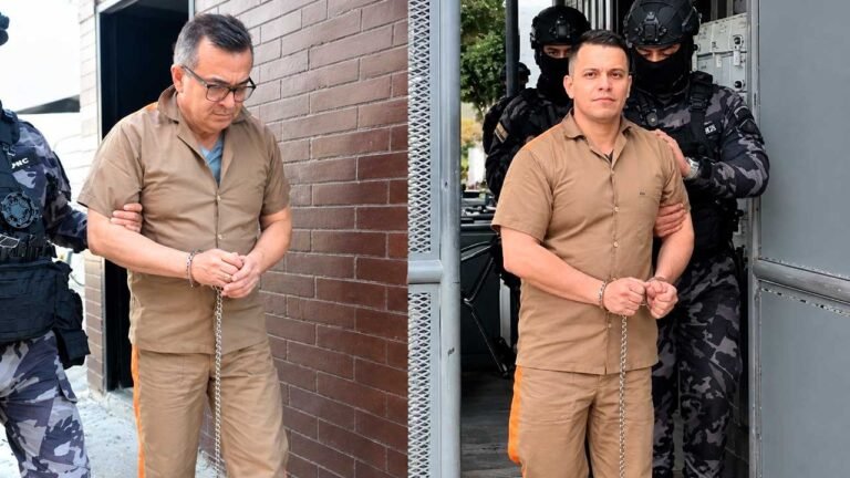 Olmedo López y Sneyder Pinilla, con uniforme carcelario y esposados, son conducidos por guardias del Inpec