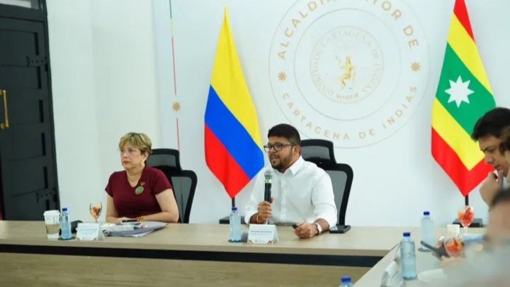 Funcionarios de la Alcaldía de Cartagena sentados en una mesa de reunión frente a las banderas de Colombia y de Cartagena