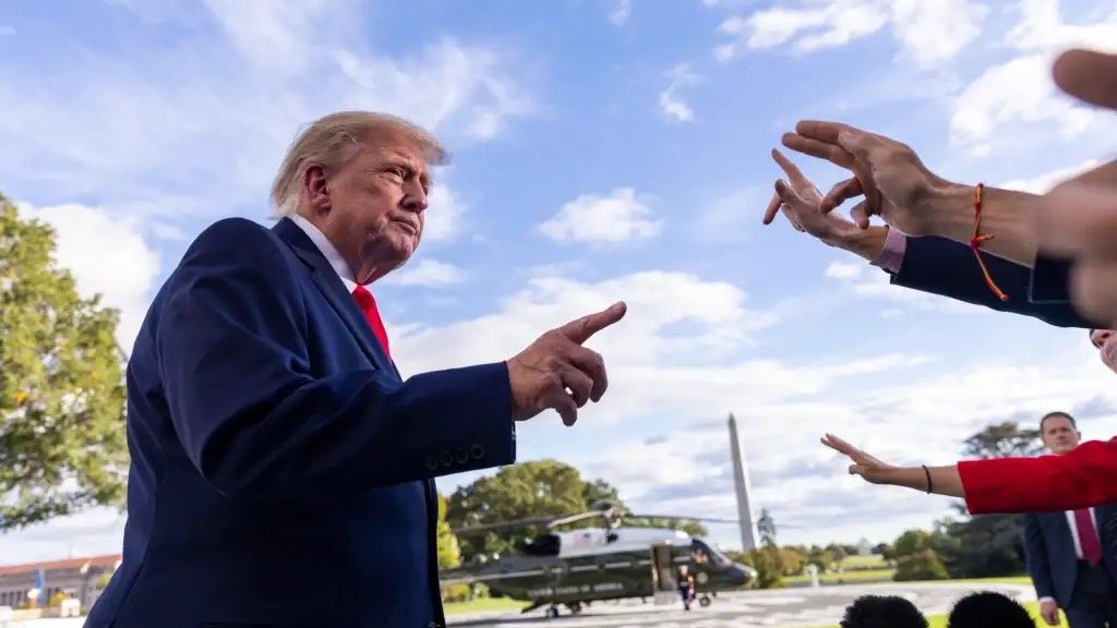 Donald Trump, de traje azul y corbata roja, señala con el dedo mientras responde a periodistas en los jardines de la Casa Blanca